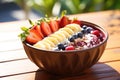 Healthy breakfast bowl with oatmeal, berries and fruits on wooden table, A delicious, colorful acai bowl on a warm sunny day, AI