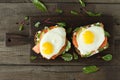 Healthy breakfast. Bread toasts with cheese, fried eggs, fish and fresh vegetables over wooden background, top view. Diet, weight Royalty Free Stock Photo