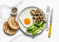 Healthy breakfast, brunch - fried egg, mixed mushrooms and green salad on a light background, top view