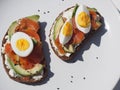 Healthy breakfast.Close up of whole grain bread sandwiches with cream cheese, egg, avocado and salmon fish on a white wooden Royalty Free Stock Photo