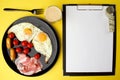 A healthy breakfast - coffee, scrambled eggs, bacon, cheese and cherry tomatoes. Food in a black plate on a yellow background. Royalty Free Stock Photo