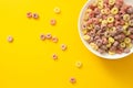 Healthy breakfast concept, Colorful ring cereals in white bowl and falling on yellow background Royalty Free Stock Photo