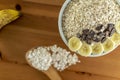 Healthy breakfast concept with oats and blurred wooden background. Wood spoon, healthy banana and dark chocolate with oats in