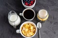 Healthy breakfast with cornflakes in a white cup, berries, milk and coffee on a dark gray background. Royalty Free Stock Photo