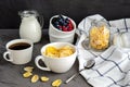 Healthy breakfast with cornflakes in a white cup, berries, milk and coffee on a dark gray background. Royalty Free Stock Photo