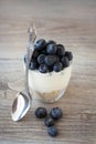 Healthy breakfast or dessert concept with fresh blueberries and muesli in a transparent glass with a spoon on a wooden background. Royalty Free Stock Photo