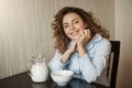 Healthy breakfast in family circle. Beautiful young mother with curly hair wearing nightwear leaning on hands while Royalty Free Stock Photo