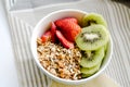 Healthy breakfast fresh granola, muesli in bowl with cereal, nuts, banana fruit, honey with drizzlier, glass of water