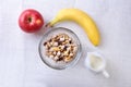 Healthy breakfast. Fresh granola, muesli with coconut, banana apple and nuts with milk in a white bowl on textile Royalty Free Stock Photo