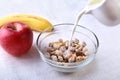 Healthy breakfast. Fresh granola, muesli with coconut, banana apple and nuts with milk in a white bowl on textile Royalty Free Stock Photo