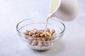 Healthy breakfast. Fresh granola, muesli with coconut, banana apple and nuts with milk in a white bowl on textile Royalty Free Stock Photo