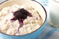 Healthy breakfast with a glass of milk, homemade oatmeal with blackberries in a blue bowl and fresh cereal bread on a light