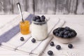 A healthy breakfast of Greek yogurt in a glass jar and fresh blueberries and jam at a rustic white table. Selective focus on glass Royalty Free Stock Photo