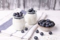 A healthy breakfast of Greek yogurt in glass jars and fresh blueberries at a rustic white table. Selective focus on glass jar in Royalty Free Stock Photo