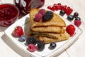 Healthy breakfast, homemade classic russian pancakes with fresh berry and raspberry confiture, white wooden background Royalty Free Stock Photo