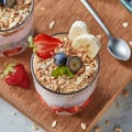 The glass with oat flakes, banana fruits, strawberries, fresh smoothie, chia seeds on a wooden board.