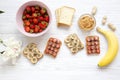 Healthy breakfast with ingredients, dieting concept. Vegan toasts with fruits, seeds, peanut butter over white wooden background, Royalty Free Stock Photo