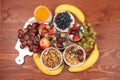 Healthy breakfast with ingredients, flat lay, fruit salad with granola, grapes, bananas, strawberries and apple on a wooden table Royalty Free Stock Photo