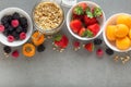 Healthy breakfast ingredients. Granola in open glass jar, blackberry, strawberry, raspberry and apricots on grey stone background