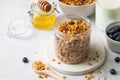 Homemade granola with raisin, seeds, hazelnut and peanut in glass jar, milk bottle, honey and blueberries on grey background. Royalty Free Stock Photo