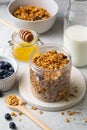 Homemade granola with raisin, seeds, hazelnut and peanut in glass jar, milk or yogurt bottle, honey and blueberriesd. Royalty Free Stock Photo