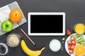 Healthy Breakfast Ingredients Oats Green Apple Banana Strawberries Kiwi Oranges Yogurt Juice on Black Table Top. Mockup Tablet Royalty Free Stock Photo