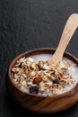 Healthy breakfast muesli and granola with skimmed milk in clear glass on black stone background