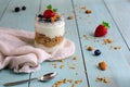 Healthy breakfast of natural yogurt with strawberries, blueberries, granola, almonds. Rag, spoon, ingredients on the table.