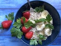 Healthy breakfast oatmeal, bananas and strawberries on wooden background.