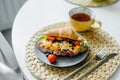 Healthy breakfast. Plate with croissant sandwich with ham, scramble egg, tomato with tea on table Royalty Free Stock Photo