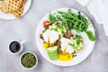 Healthy breakfast. Poached eggs on toast with avocado pieces, arugula, mizuna and chard leaves and cherry tomatoes on a plate Royalty Free Stock Photo