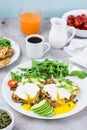 Healthy breakfast. Poached eggs on toast with avocado pieces, arugula, mizuna and chard leaves and cherry tomatoes on a plate on a Royalty Free Stock Photo