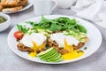 Healthy breakfast. Poached eggs on toast with avocado pieces, arugula, mizuna and chard leaves and cherry tomatoes on a plate on a Royalty Free Stock Photo