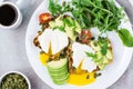 Healthy breakfast. Poached eggs on toast with avocado pieces, arugula, mizuna and chard leaves and tomatoes on a plate on a served Royalty Free Stock Photo