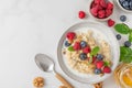 Healthy breakfast. Quinoa porridge with fresh berries, nuts and mint in a bowl with spoon on white background. top view