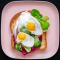 Healthy breakfast sandwiches concept. Bread toasts with fried eggs and green salad on pink plate on black Royalty Free Stock Photo