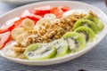 Healthy breakfast served with plate of yogurt muesli kiwi strawberries and banana