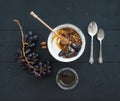 Healthy breakfast set. Bowl of oat granola with yogurt, fresh grapes, almond and honey over black wooden backdrop Royalty Free Stock Photo