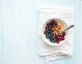 Healthy breakfast set. Bowl of oat porridge with fresh berries, almond and honey over white napkin. Top view, light blue Royalty Free Stock Photo