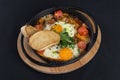 Healthy breakfast shakshuka - fried eggs, onion, bell pepper, tomatoes and spices in cast iron stewpan on old wooden plank Royalty Free Stock Photo