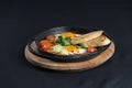 Healthy breakfast shakshuka - fried eggs, onion, bell pepper, tomatoes and spices in cast iron stewpan on old wooden plank Royalty Free Stock Photo