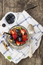 A healthy breakfast snack from granola, vanilla chia pudding, strawberries, blueberries in a large serving glass on a