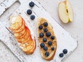 Healthy breakfast with sweet sandwiches - ricotta, blueberries, apple slices, peanut butter on white rustic wood table