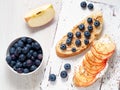 Healthy breakfast with sweet sandwiches - ricotta, blueberries, apple slices, peanut butter on white rustic wood table Royalty Free Stock Photo