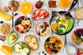 Healthy breakfast table scene with fruit, yogurts, oatmeal, smoothie bowl, cereal, nutritious toasts and egg skillet, top view ove Royalty Free Stock Photo