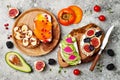 Healthy breakfast toasts with peanut butter, banana, chocolate granola, avocado, persimmon, figs