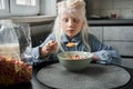 Girl looking at the spoon attentively while eating corn flakes with milk Royalty Free Stock Photo