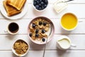 Healthy breakfast of whole wheat flakes with milk, blueberries, cup of coffee, orange juice and toast on white wooden table. Top Royalty Free Stock Photo