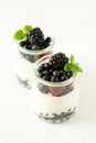 Healthy breakfast: yogurt with strawberry, blueberry and blackberry decorated mint leaves on white wooden table Royalty Free Stock Photo