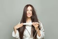 Healthy brunette woman straighten her hair with straightener on white background. Haircare concept